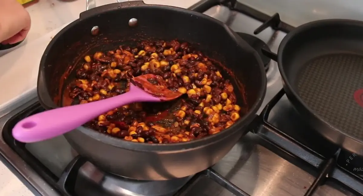 Chipotle Black Bean Tacos filling, with added spices, simmering in a pot on the stove.