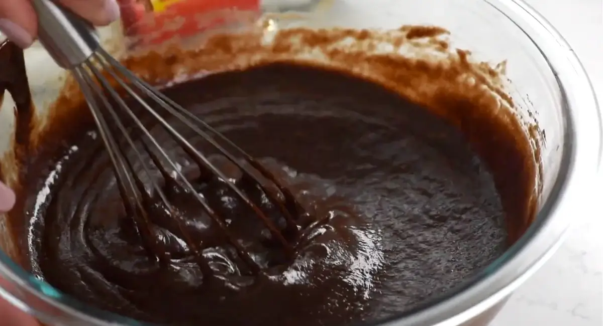 Whisking the chocolate filling for a Texas Chocolate Pecan Pie in a glass bowl.