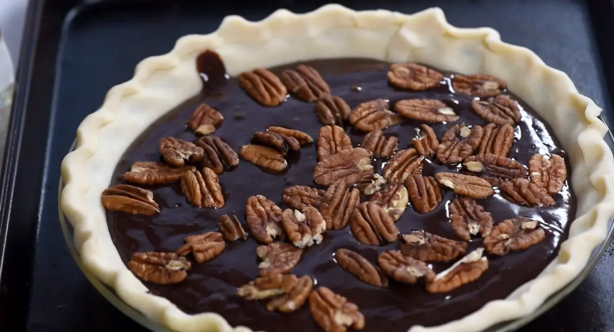 Unbaked Texas Chocolate Pecan Pie with pecan halves arranged on top of the chocolate filling.