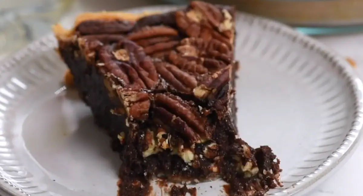 Slice of Texas Chocolate Pecan Pie on a white plate, showing the layers of crust, chocolate filling, and pecans.