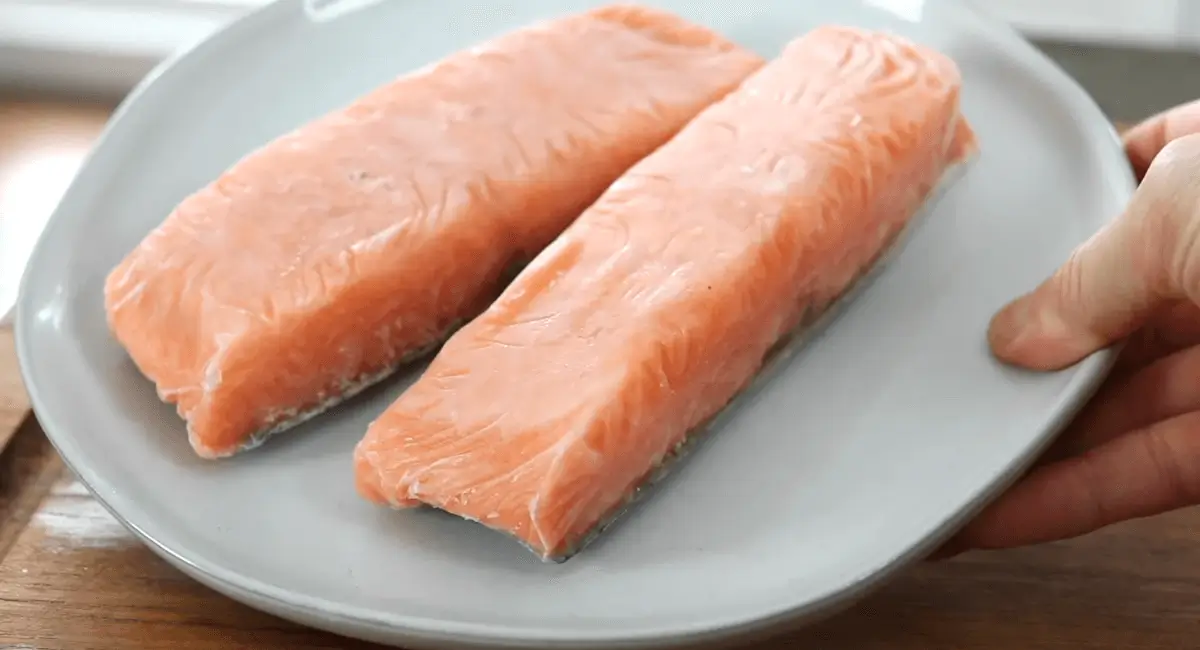 Frozen salmon fillets on a plate, ready to be cooked in an air fryer.