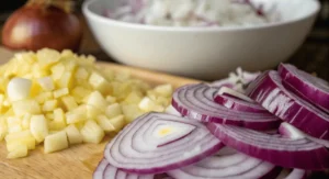 Chopped red onions and diced garlic on a cutting board.