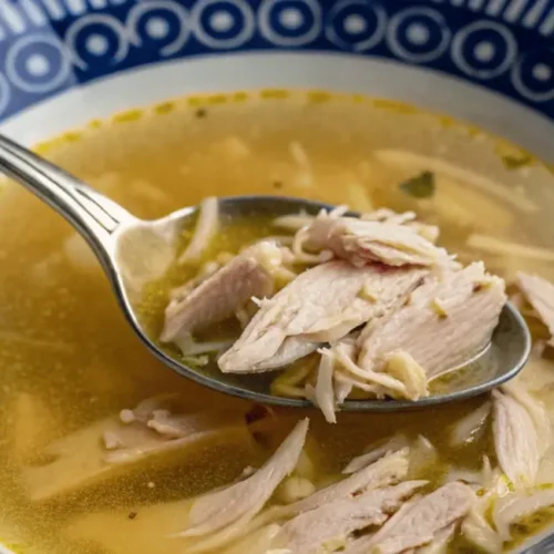 Bowl of chicken drumstick soup with shredded chicken and broth.