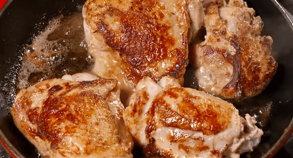 Golden-brown chicken thighs searing in a pan, a key step in making Ranch Chicken and Rice.