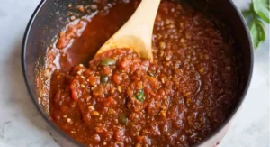 Wooden spoon stirring chunky Homemade Spaghetti Sauce in a pot