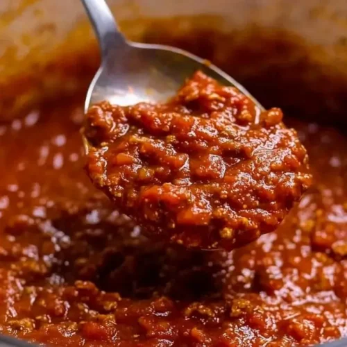 Spoon lifting thick Homemade Spaghetti Sauce from a pot