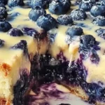 Nova Scotia Blueberry Cream Cake Recipe 10 Close-up of a Nova Scotia Blueberry Cream Cake with a slice cut out, showcasing the creamy filling and blueberry texture.