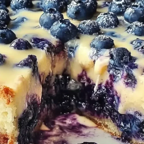 Close-up of a Nova Scotia Blueberry Cream Cake with a slice cut out, showcasing the creamy filling and blueberry texture.