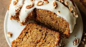 Close-up slice of moist carrot bundt cake recipe with cream cheese glaze and pecans, showcasing the delicious texture.