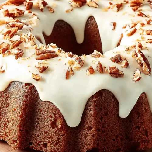 Irresistible carrot bundt cake recipe with sweet cream cheese frosting and pecan garnish.