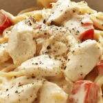 Bowl of creamy chicken spaghetti with tomatoes and black pepper.