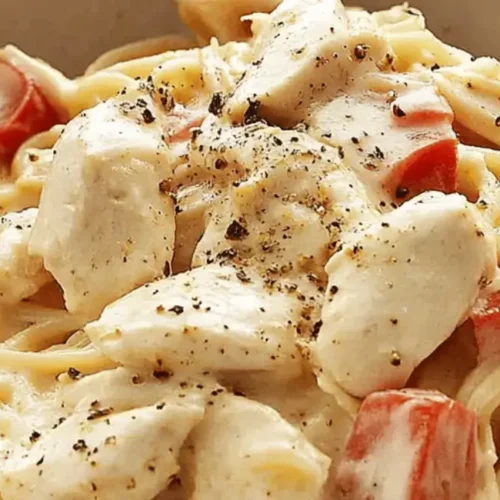 Bowl of creamy chicken spaghetti with tomatoes and black pepper.