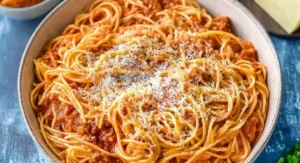 A close-up shot of a large bowl filled with crockpot spaghetti topped with grated cheese.