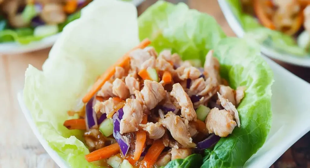 A single Healthy Honey Chicken Lettuce Wrap on a white surface.