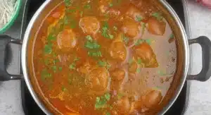 A pot of simmering Kashmiri Rajma Curry Recipe with visible spices and herbs.