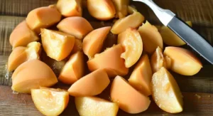 Close-up of sliced apricots on a wooden cutting board, part of an apricot cobbler recipe preparation.