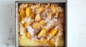 A square baking dish filled with baked apricot cobbler recipe, dusted with powdered sugar.