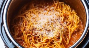 A stainless steel instant pot filled with freshly cooked instant pot spaghetti in a savory tomato-based sauce, topped with grated Parmesan cheese.
