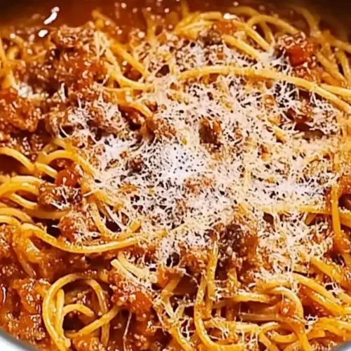 Close-up of instant pot spaghetti with a hearty meat sauce and grated Parmesan cheese in a stainless steel instant pot.