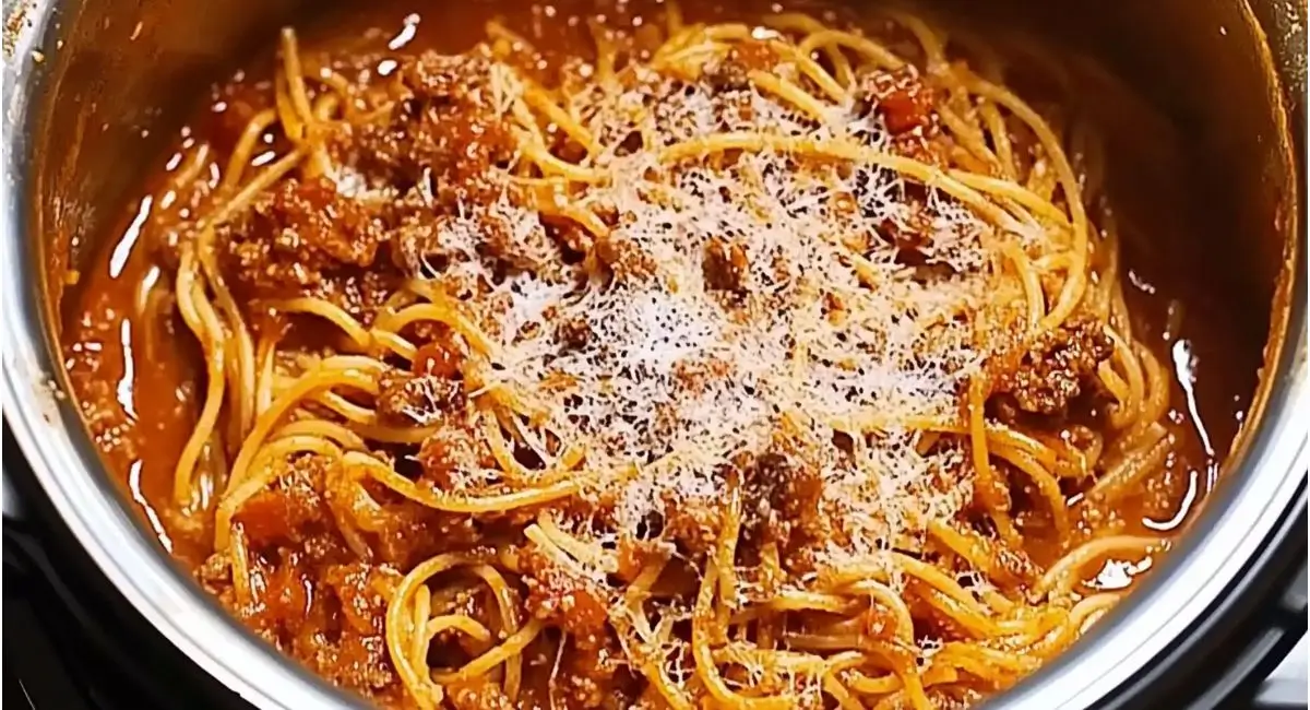 Close-up of instant pot spaghetti with a hearty meat sauce and grated Parmesan cheese in a stainless steel instant pot.