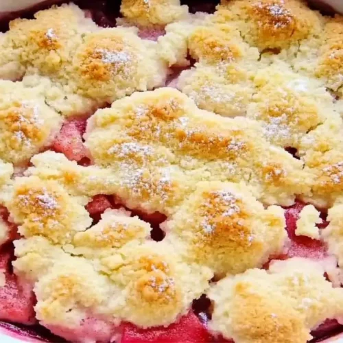 A freshly baked rhubarb cobbler in a white dish, featuring a golden crumble topping, part of a rhubarb cobbler recipe.