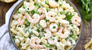 Bowl of shrimp pasta salad recipe with elbow macaroni, shrimp, green peas, and parsley.