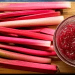 Fresh rhubarb stalks next to a bowl of stewed rhubarb compote
