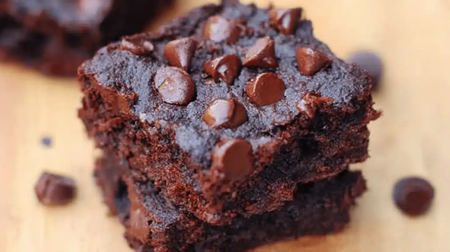 Close-up of fudgy flourless black bean brownies stacked and topped with melted chocolate chips.